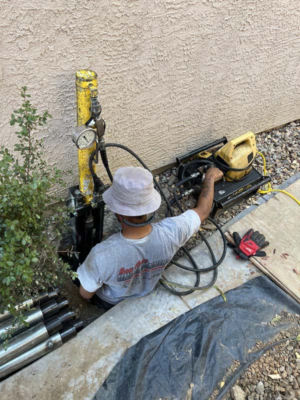 crew installing push piers under a house foundation
